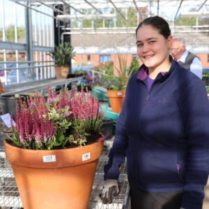 Female Gardens and Plant Production student in the glasshouse with display pot