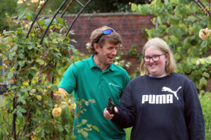 Horticulture student and staff looking at roses in the walled garden