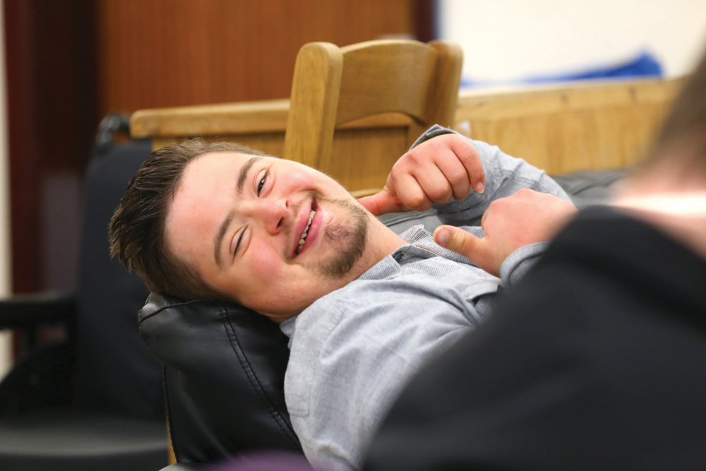 Person relaxing, smiling at the camera with his thumbs up.