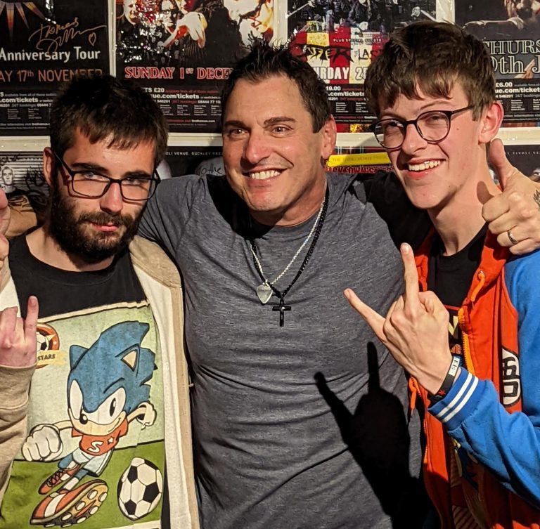 Derwen students Ethan and Joe (making rock hand gestures) get a hug from Hardline frontman Johnny.