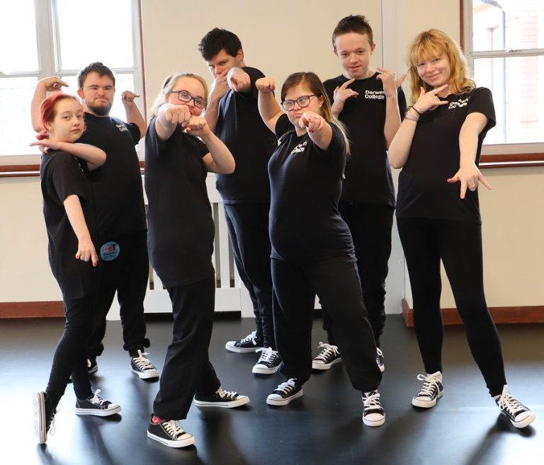 Seven members of Derwen Dance Crew - dressed in DDC black t-shirts - strike a street dance pose