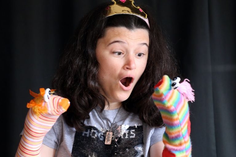 Amy performs stories to children with a stripy sock puppet on each hand