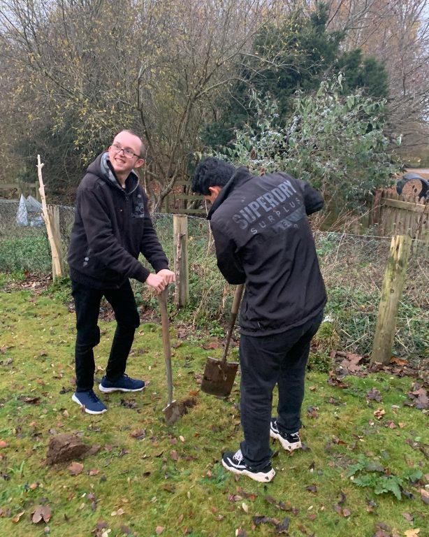 Two Duke of Edinburgh's Awards students use spades to prepare the ground for the planting of a tree.