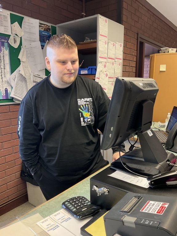 Business student Aaron working on the till in the Derwen College Garden Centre and Gift Shop.