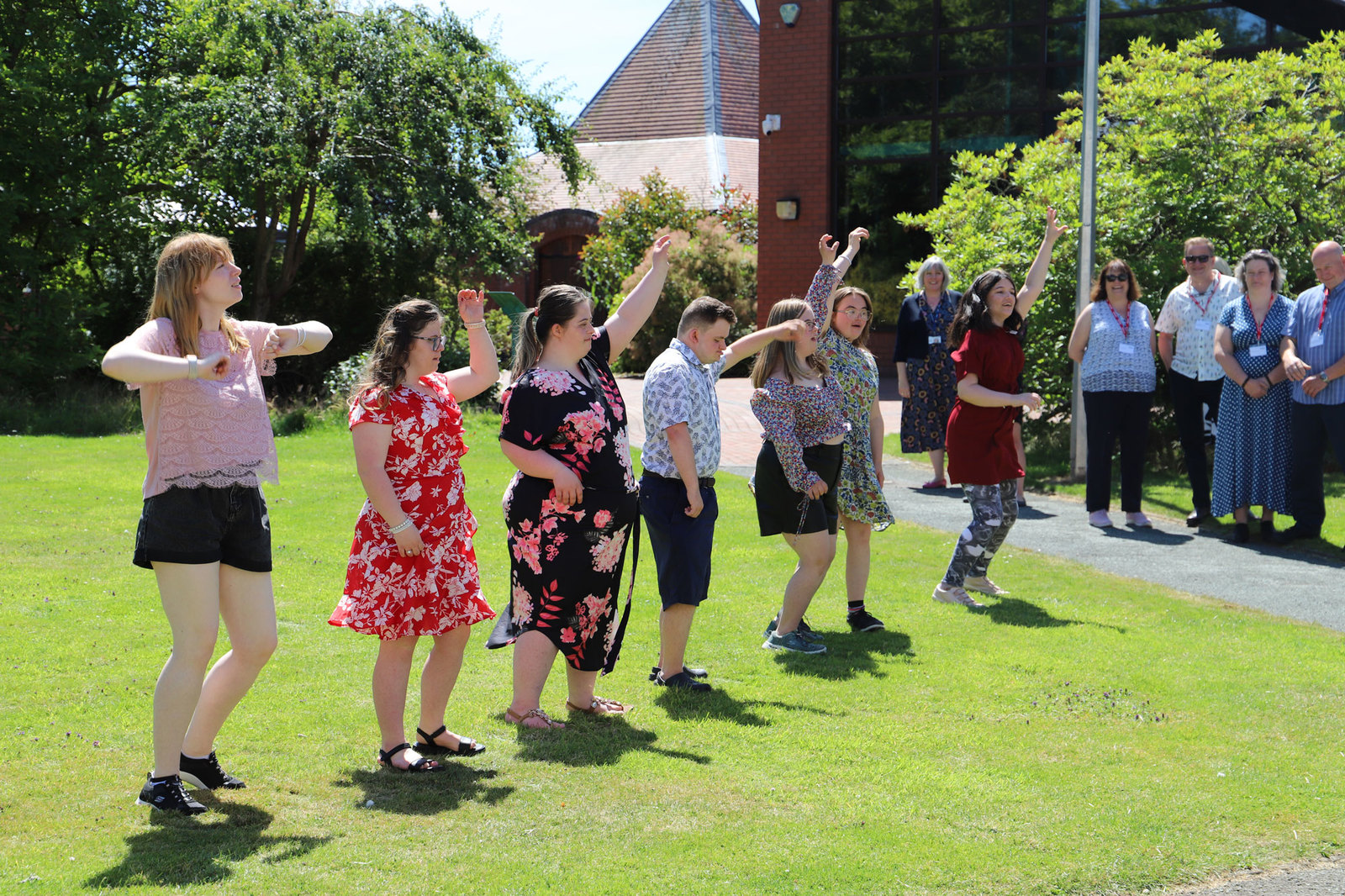 Derwen On Tour perform on a lawn on a bright sunny day, in front of a small audience