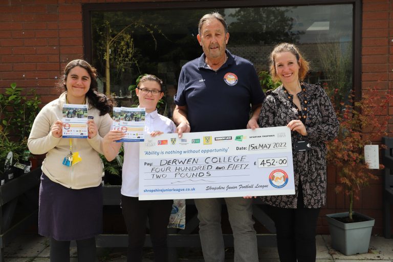 Two students stand next to Mike from Shropshire Junior Football League who is presenting Anna, fundraiser with a charity donation.