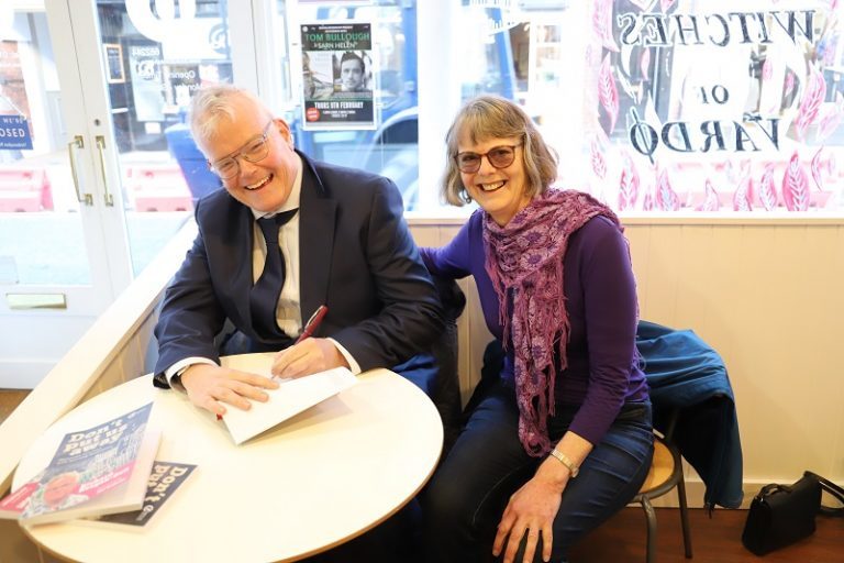 Richard Keagan-Bull and his friend and assistant Hazel Bradley sit at a table in Booka Bookshop signing copies of his autobiography.