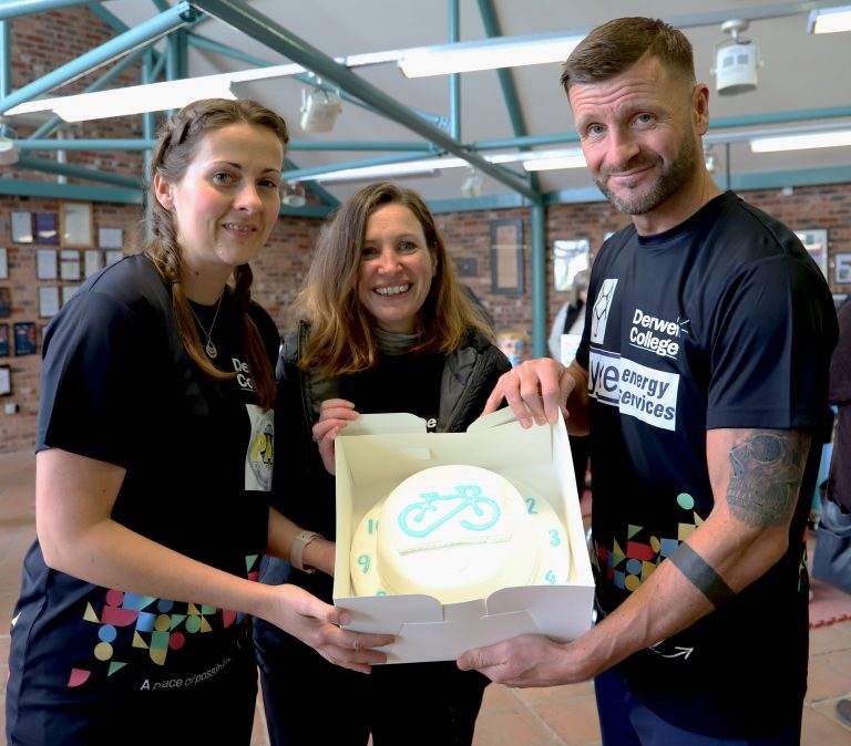 Sian, Anna and Steve hold up a cake to celebrate 24 spinathon