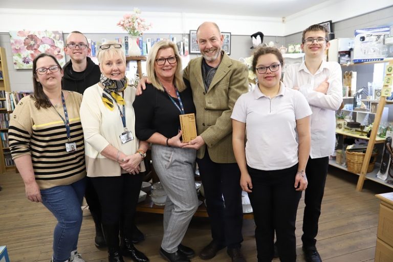Retail assistant Ruth Bellamy, student George Evans, Retail Assistant Karen Hughes, Commercial Supervisor Sharon Jones, Commercial Manager Pete Evans, student Abigail Munroe and student Henry Stott in a group photo in the charity shop holding the Charity Retail Award.
