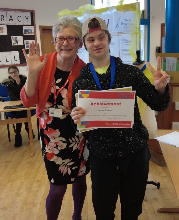 Local author Jan Hedger smiles and waves with student Lucas who holds up a third place certificate and gives the sign for peace. 