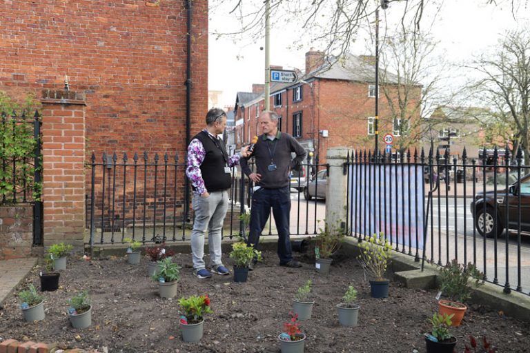 Radio presenter Paul Shuttleworth interviews nursery manager Paul Moss in Cae Glas Park, surrounded by pots of plants ready to be planted.