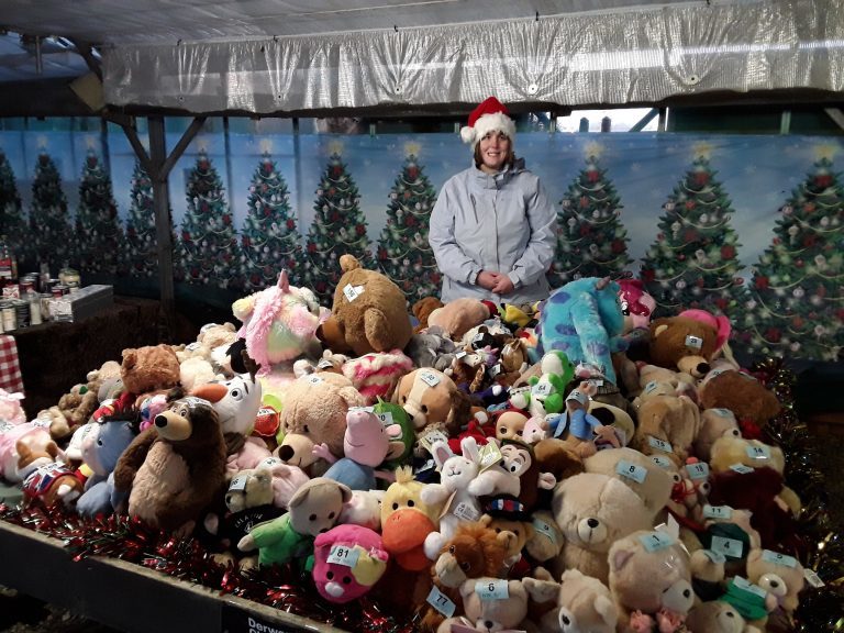 Student stand behind a table full of teddies