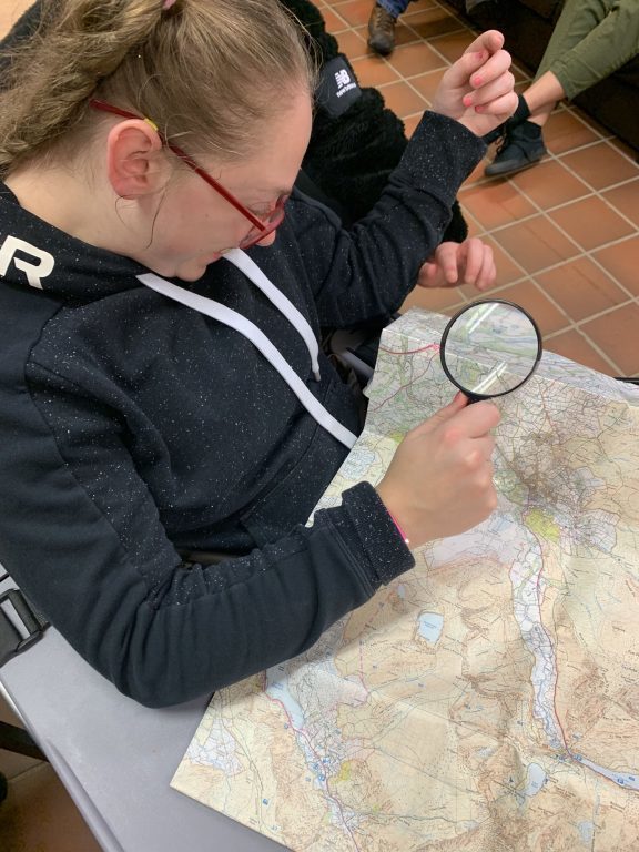 Bronze DofE student studies a map with a magnifying glass