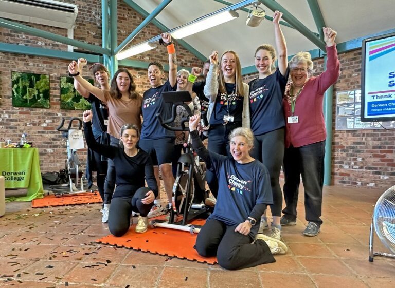 Group photo of spinners, organisers and supporters with arms in the air.