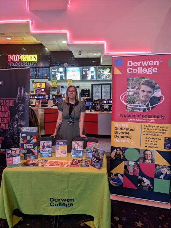 person standing behind a stall promoting Derwen College