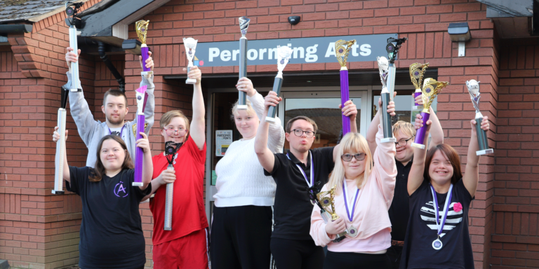 performing arts students holding up competition trophies