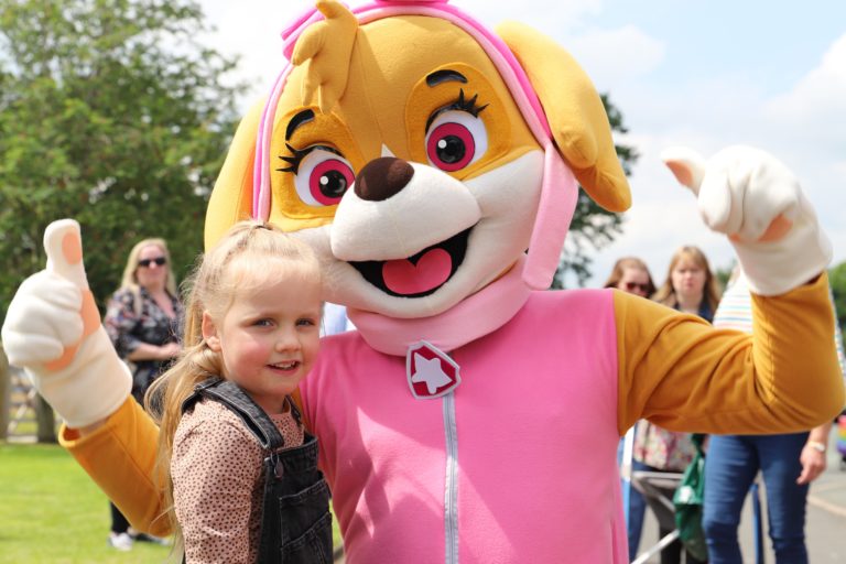 girl standing next to a dog character
