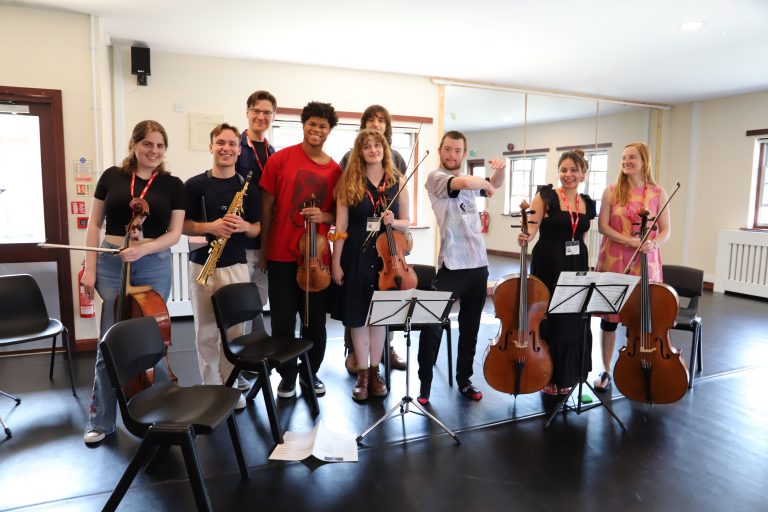 Eight musicians, holding cello, violins or saxophone, stand in a group with student Dan.