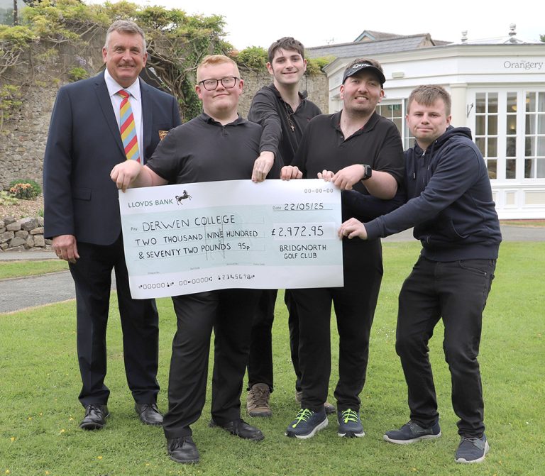 Bridgnorth Golf Club captain, wearing a suit and tie, hands over a giant cheque for £2,972.95 to four smiling male students all wearing uniform of black polos and trousers. They are stood outside on the lawn in front of The Orangery Restaurant.