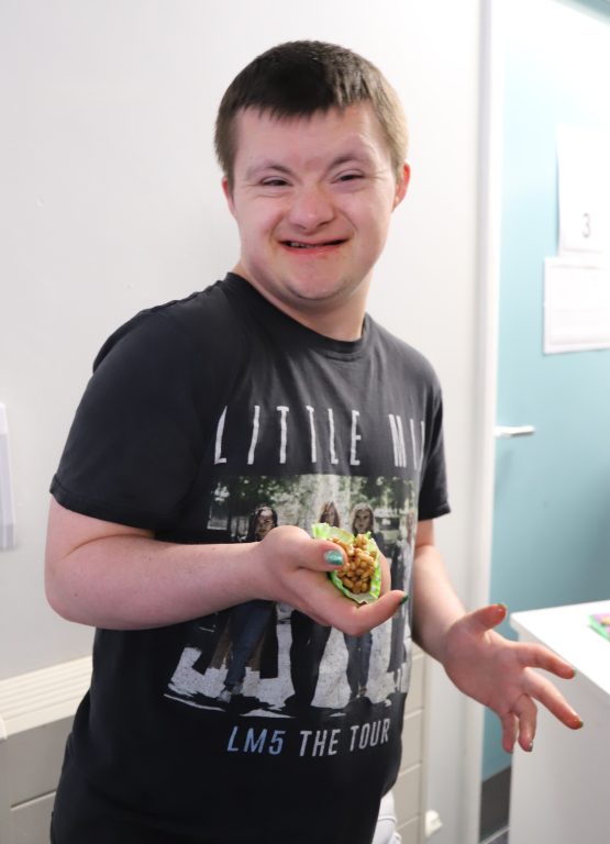 A smiling student holds a crispy cake