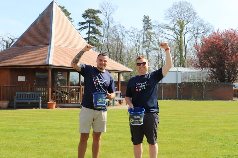 Derwen Charity runners wearing Derwen Charity t-shirts and shorts, hold Derwen Charity collection buckets and have their fists in the area.