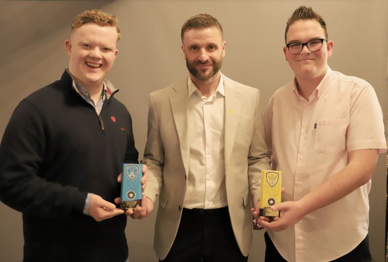 Two students and their teacher, dressed smartly, holding two Cricket Shropshire Awards