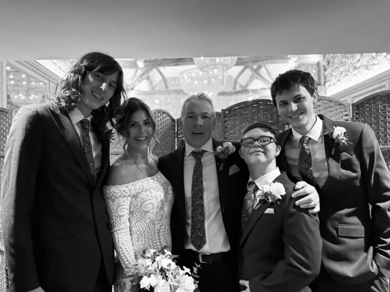 black and white wedding photo of bride and groom Caroline and Steven with suited Joe and his stepbrothers Tom and