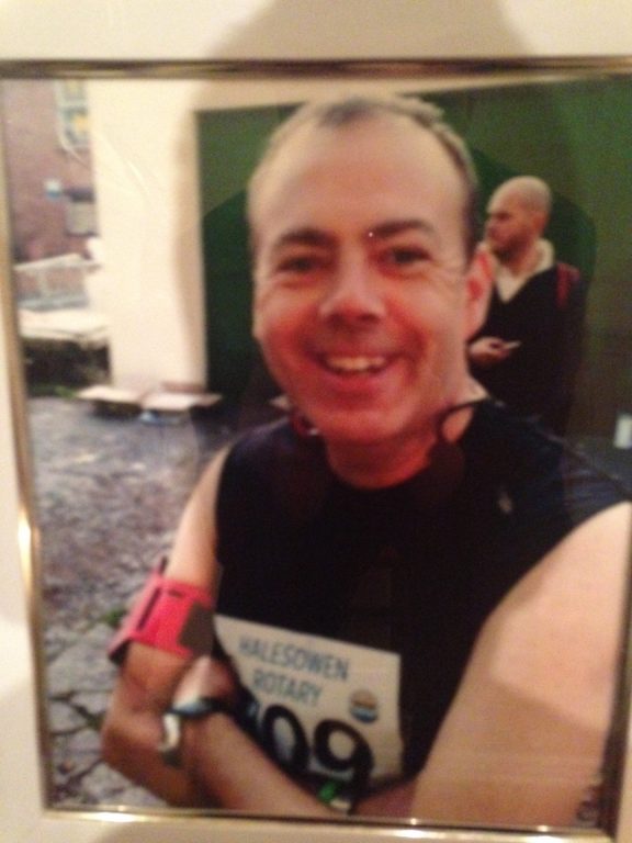 Blurry photo of Connor's Dad smiling and wearing a running vest and race number.