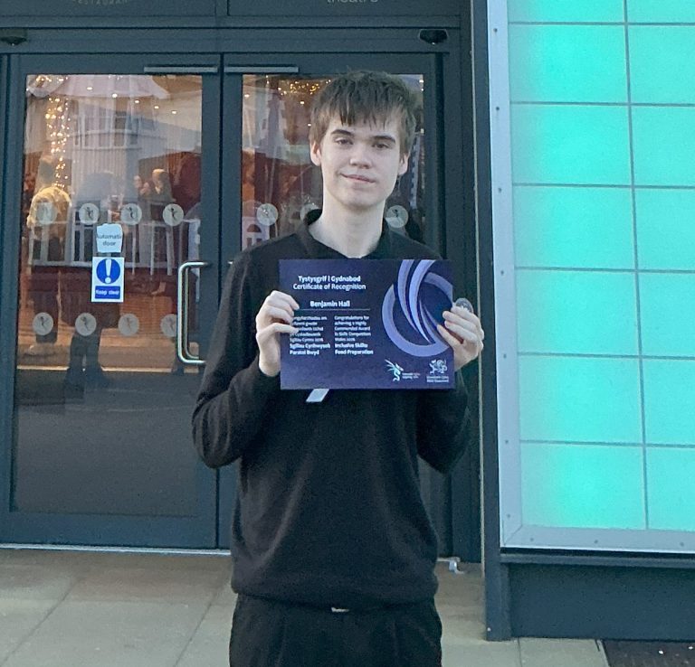 Student holding a highly commended certificate outside Rhyl Pavilion.