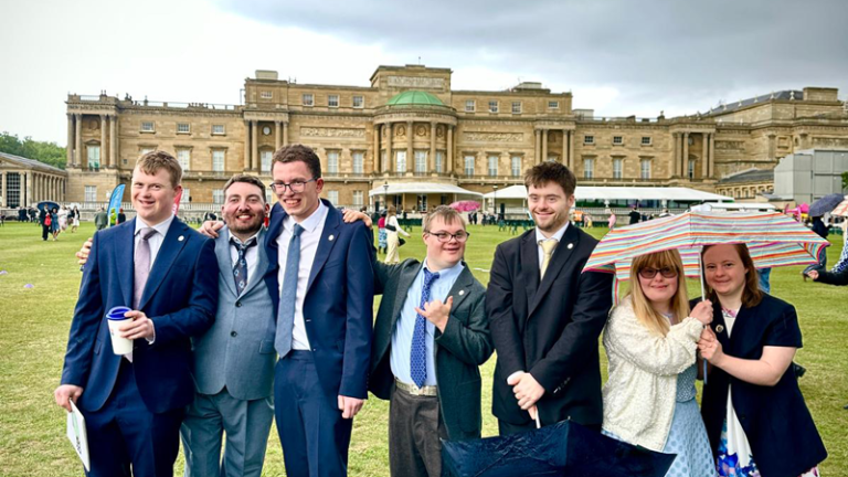 students stood with buckingham palace in the background