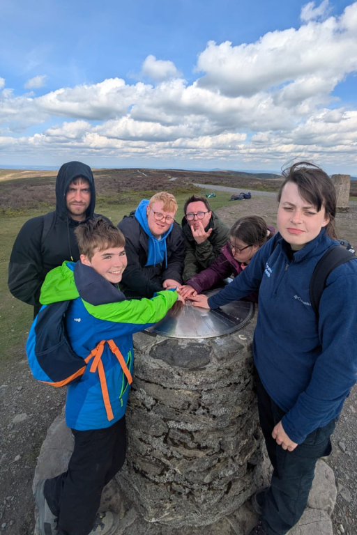 students standing around a trig point on the long mynd