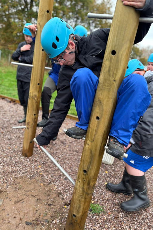 student on a climbing pole doing the peg pole challenge