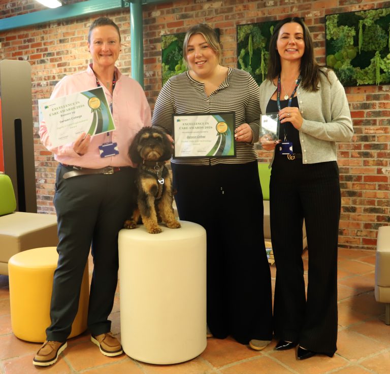 Three staff members holding certificates and an award along with very cute therapy dog Mr Pickles.