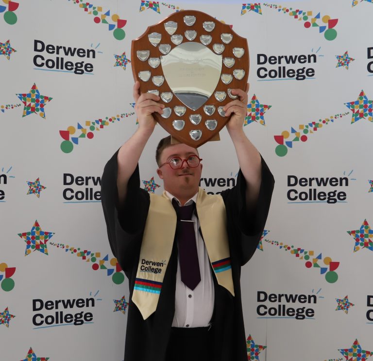 Student in gown and sash holding large shield